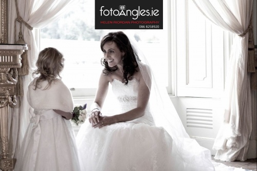 Smiling bride chats with flowergirl by bay window